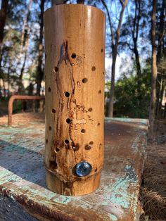 a wooden object with holes in it sitting on top of a piece of wood near trees