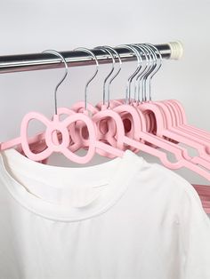 several pink hangers are hanging on a metal rack next to a white t - shirt