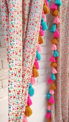 colorful tasselled curtains hanging on a brick wall