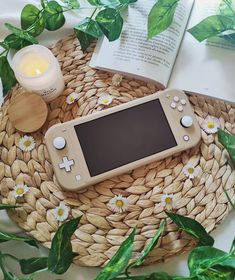 a cell phone sitting on top of a wicker basket next to a candle and book