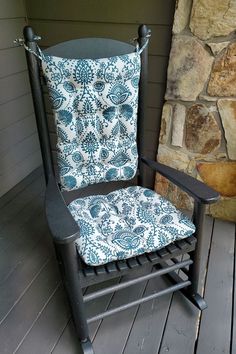 a black rocking chair with a blue and white pillow on it's backrest