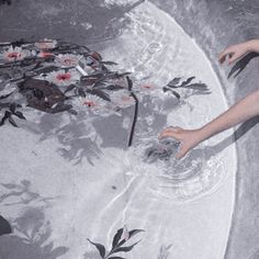 two hands reaching for flowers in a water fountain