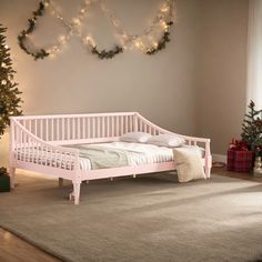 a white bed sitting on top of a wooden floor next to a christmas tree