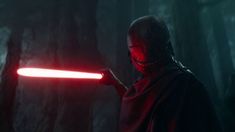 darth vader in the dark forest holding a light saber up to his face