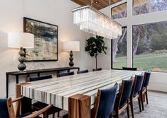 a dining room table with blue chairs and a chandelier hanging from the ceiling