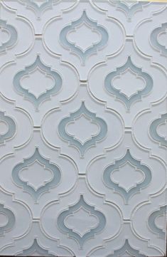 a white tile wall with an intricate pattern on it