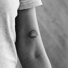 a person with a tattoo on their arm and the sun in the sky behind them