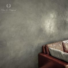 a brown leather couch sitting in front of a gray wall