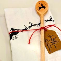 a wooden spoon sitting on top of a white napkin next to a tag with santa's sleigh