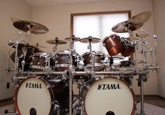 a drum set sitting on top of a carpeted floor in front of a window