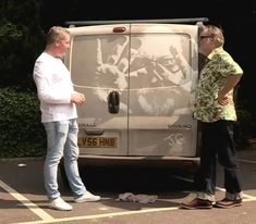 two men standing in front of a van with graffiti on the side and another man looking at it