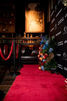 a red carpet with flowers on it in front of a black backdrop