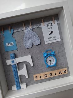 a shadow frame with clothes and a clock on the wall next to letters that spell out florida