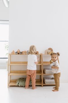 two toddlers playing with toys in their playroom at the same time as they stand next to each other