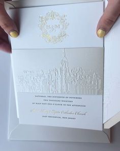 a person holding up a white and gold wedding card