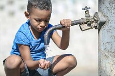 a young boy is playing with a water faucet in front of a fire hydrant