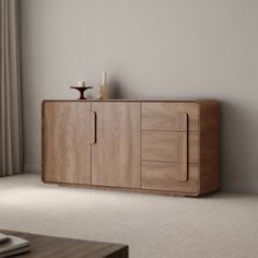 a wooden cabinet sitting in front of a window next to a table with a candle on it