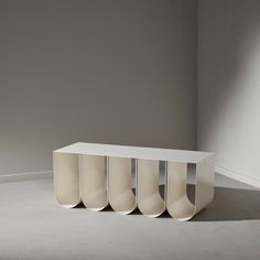 a white table with four vases sitting on it's sides in front of a gray wall