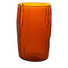 an orange glass vase sitting on top of a white surface with no one around it