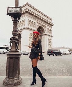 a woman standing next to a lamp post in front of the arc de trioe