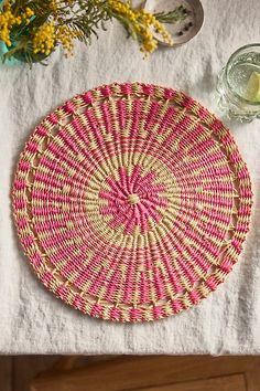 a pink and white plate sitting on top of a table next to a vase with yellow flowers