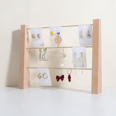 a wooden display with earrings and jewelry hanging from it's sides on a white surface