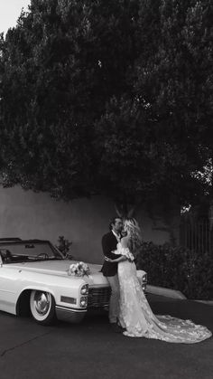 a bride and groom standing next to a vintage car