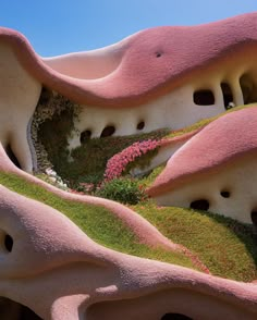 an unusual building with pink and green plants growing on it's sides, in the shape of mountains