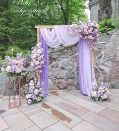 an outdoor ceremony setup with purple flowers and draping on the side of it