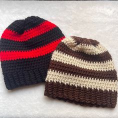 two crocheted hats sitting on top of a white table next to each other