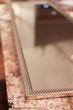 a mirror sitting on top of a marble counter next to a cup and saucer