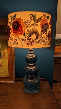 a lamp that is sitting on top of a table next to a painting and framed pictures