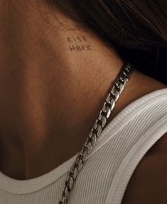 the back of a woman's neck has a tattoo on it that reads, just here