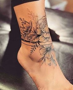 a woman's foot with flowers on it and a tattoo design on the ankle