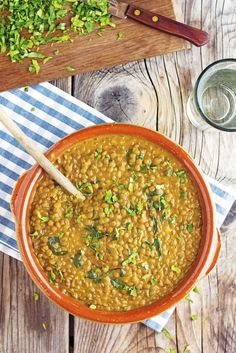 a bowl filled with beans and greens on top of a wooden table