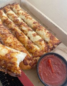 a box with some pizza sticks and sauce in it next to a bowl of ketchup