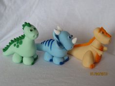 three small toy dinosaurs sitting next to each other