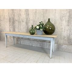 two green vases sitting on top of a wooden table next to a planter