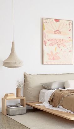 a bed sitting on top of a wooden platform next to a wall mounted art piece