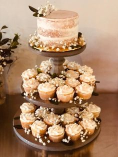 three tiered cake and cupcake display with flowers on each tier for desserts