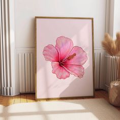 a pink flower is displayed in a frame on the floor