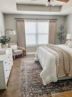 a bedroom with a bed, dressers and windows in it's center area