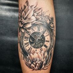 a black and white photo of a clock with flowers on the side of his leg