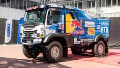 a large truck parked on top of a red carpeted floor next to a tall building