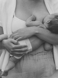 a black and white photo of a woman holding a baby in her arms with both hands