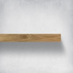 an empty wooden shelf on a white wall