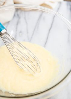 a whisk in a glass bowl filled with batter