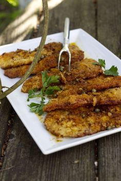 fried food on a plate with a fork stuck in it and garnished with parsley