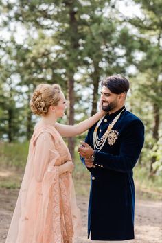 a man in a blue suit and woman in a pink dress are standing next to each other