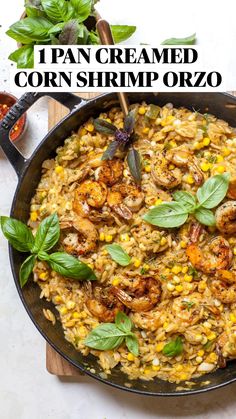 a skillet filled with shrimp and rice on top of a wooden cutting board next to some herbs